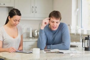 Man and woman talking in kitchen while drinking coffee and reading