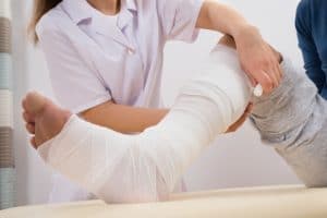 Female doctor putting bandage on patients leg