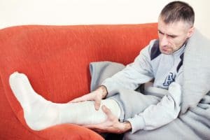 Man with broken leg ankle or foot sitting on sofa