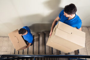 Two men carrying cardboard boxes down stairs
