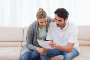 Man and woman reading letter in living room on sofa