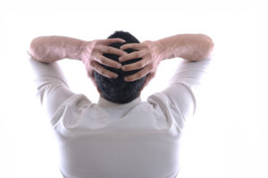 Man having headache with arms behind head