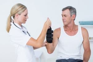 Doctor examining a mans wrist with brace and carpal tunnel syndrome