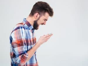 Frustrated young man with beard shouting on cell phone