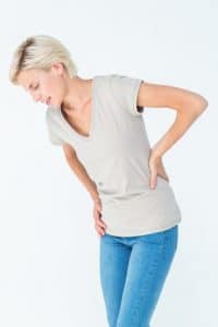 Woman suffering from hip and back pain while bending