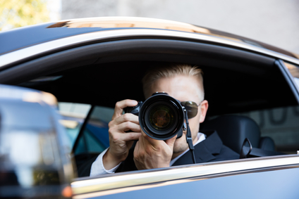 Male private investigator taking picture from car with camera