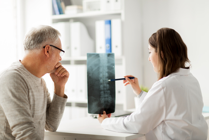 Female doctor with older man showing xray of spine and back at hospital