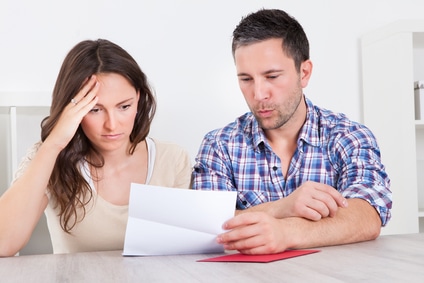 Man and woman reading letter and looking confused